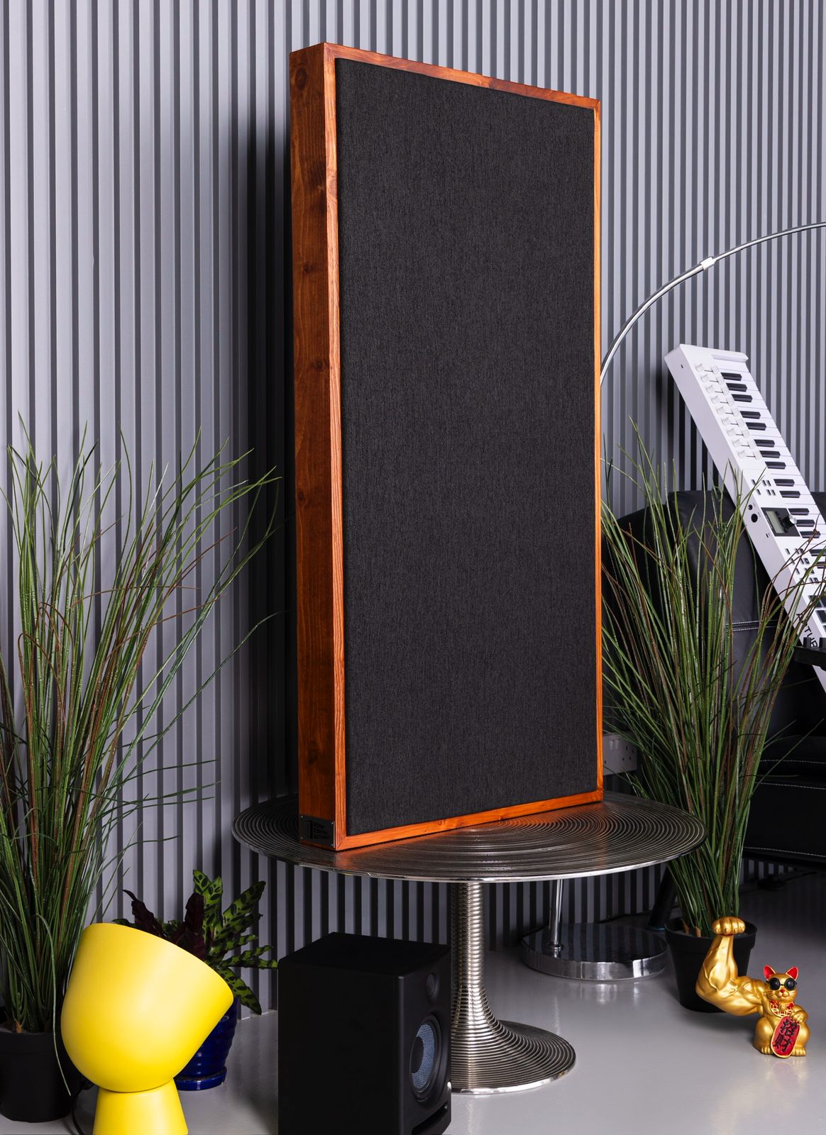 Tall black acoustic panel on a silver stand with decorative plants and a white keyboard in the background | Room Control Authority
